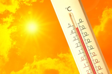 Image of Extremely high temperature on thermometer against orange sky on sunny day. Severely hot summer weather