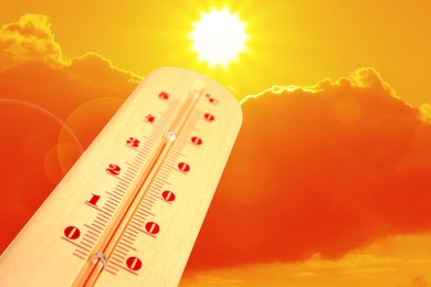 Image of High temperature on thermometer against orange sky on sunny day. Hot summer weather