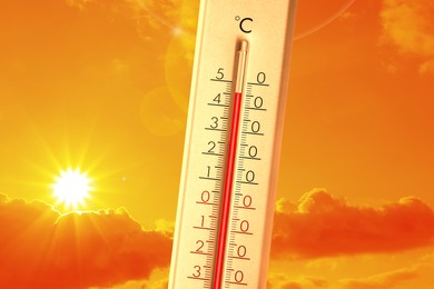 Image of Extremely high temperature on thermometer against orange sky on sunny day. Severely hot summer weather