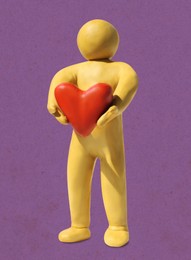 Image of Yellow plasticine human figure with red heart on purple background
