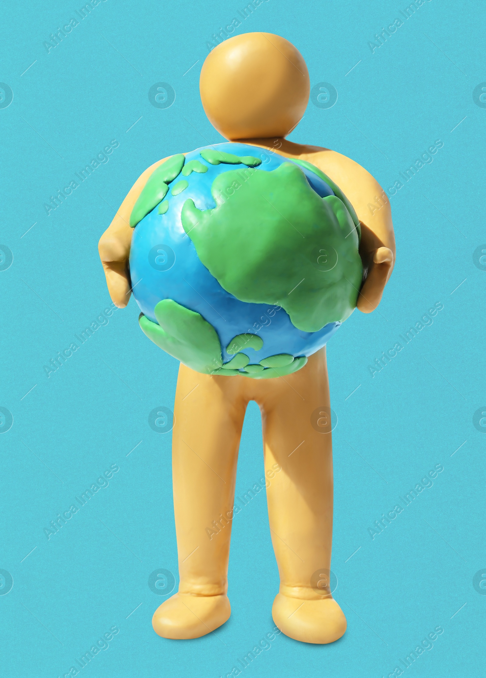 Yellow plasticine human figure holding planet on light blue background Image of Yellow plasticine human figure holding planet on light blue background