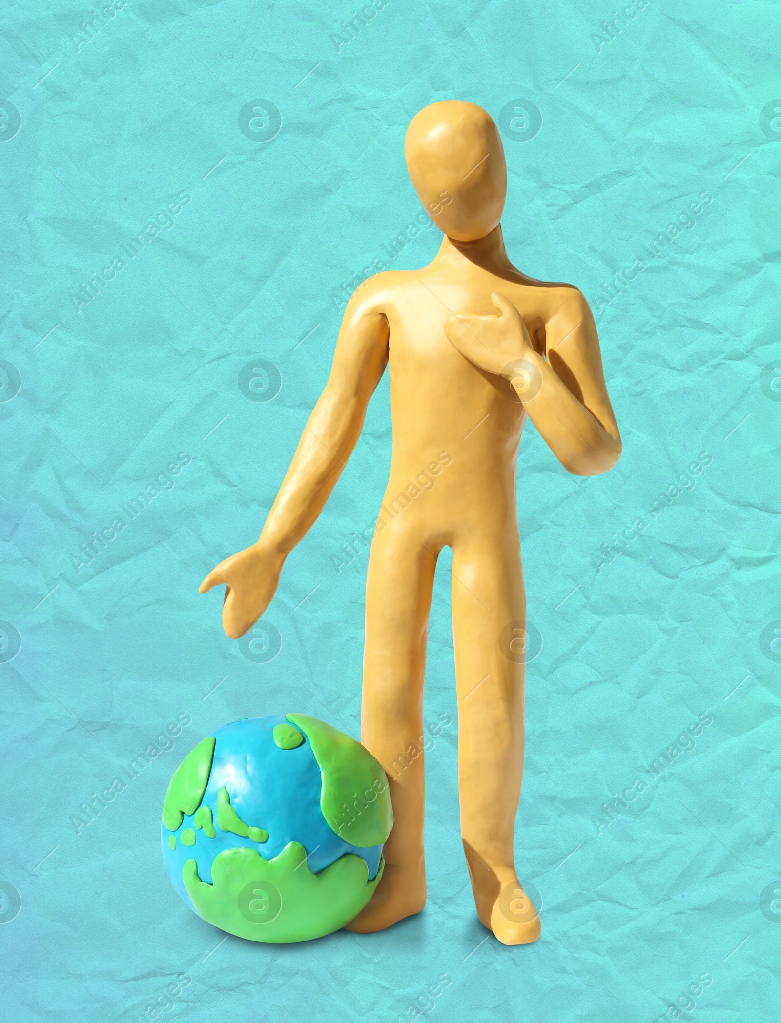 Yellow plasticine human figure with planet on turquoise background Image of Yellow plasticine human figure with planet on turquoise background