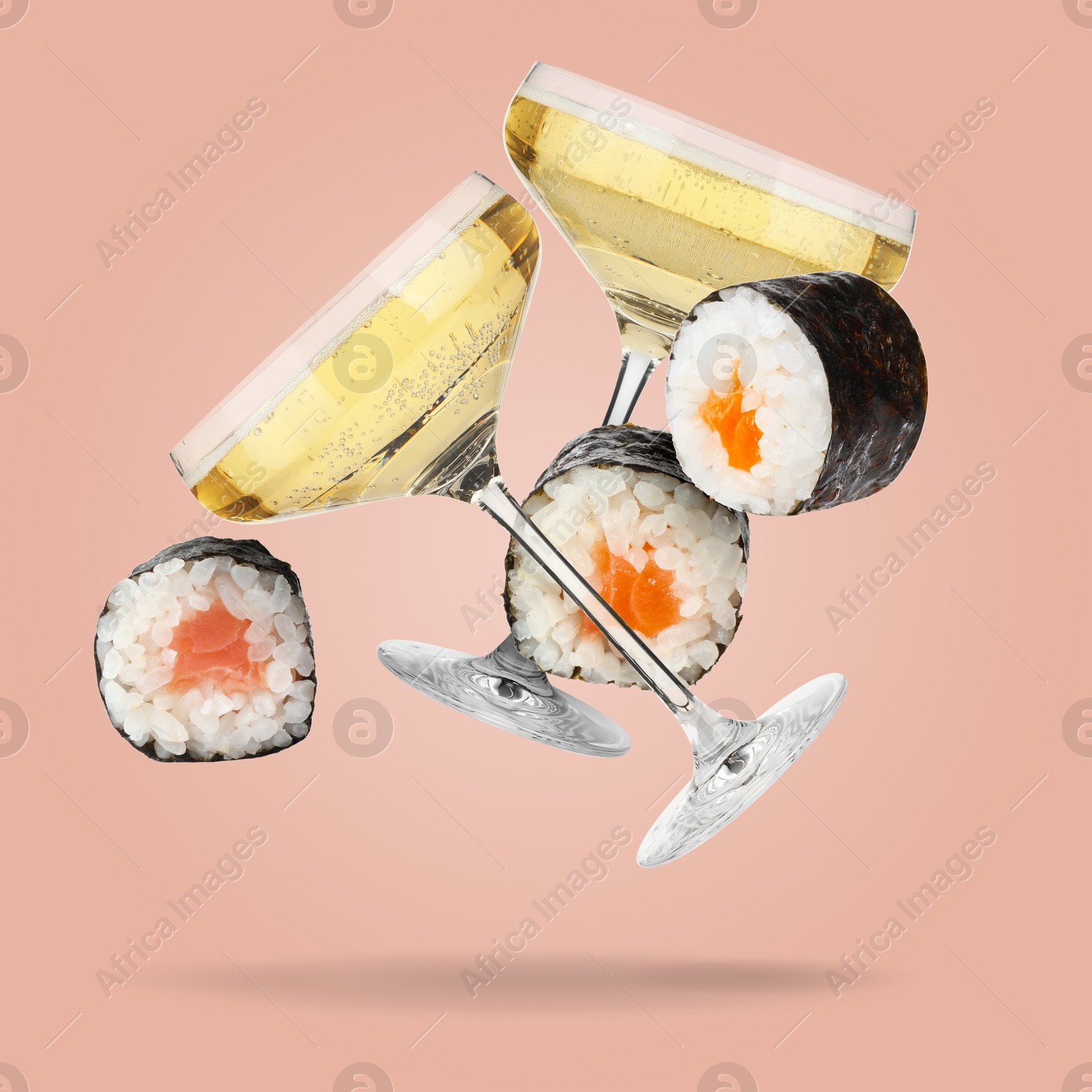 Image of Sparkling wine in glasses and sushi rolls falling on pink beige background