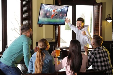 Image of Football fans watching soccer match on TV set at bar