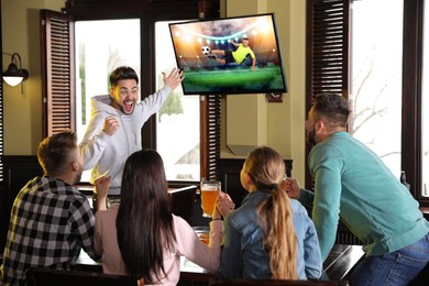 Image of Football fans watching soccer match on TV set at bar