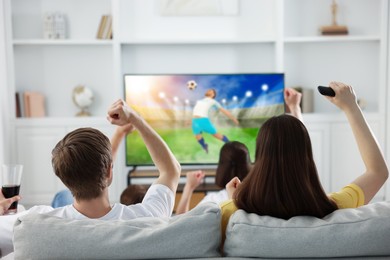 Image of Football fans watching soccer match on TV set at home, back view