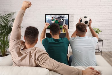 Image of Football fans watching soccer match on TV set at home, back view