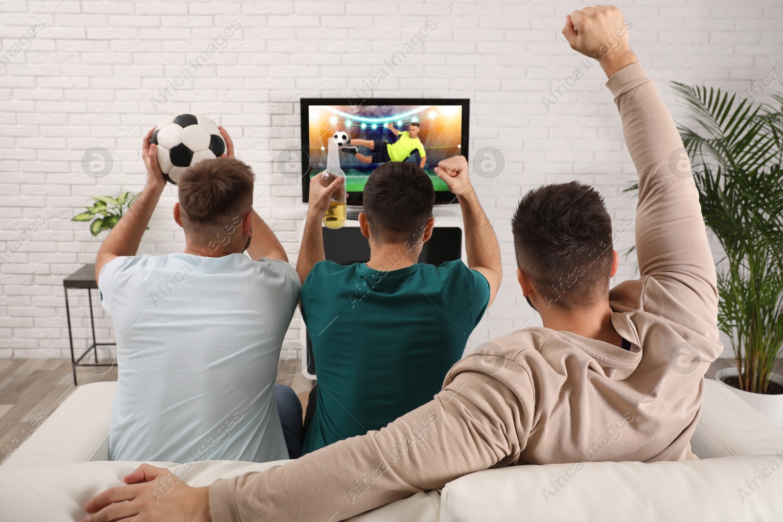 Image of Football fans watching soccer match on TV set at home, back view