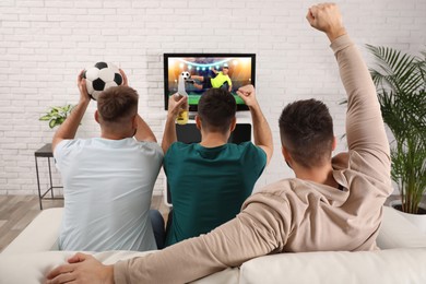 Image of Football fans watching soccer match on TV set at home, back view