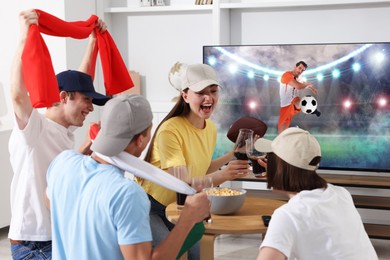 Image of Football fans watching soccer match on TV set at home