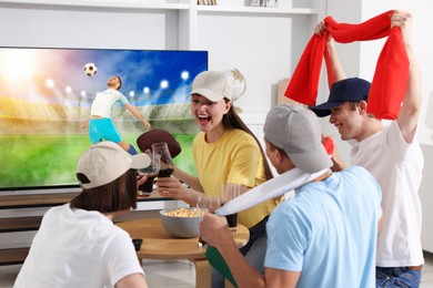 Image of Football fans watching soccer match on TV set at home
