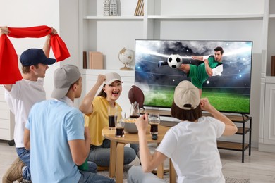 Image of Football fans watching soccer match on TV set at home