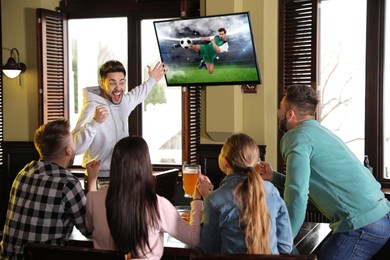 Image of Football fans watching soccer match on TV set at bar