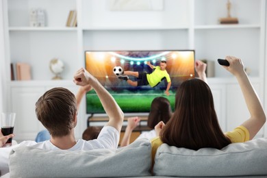 Image of Football fans watching soccer match on TV set at home, back view
