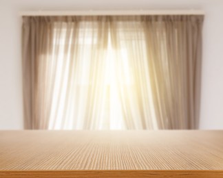 Image of Empty wooden table against window with curtains in room
