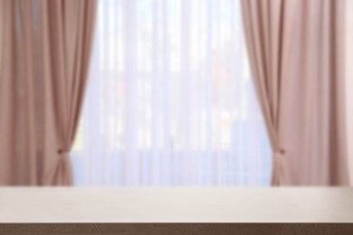Image of Empty table against window with curtains in room