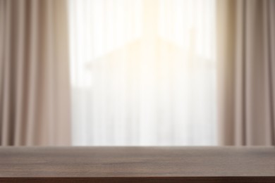 Image of Empty wooden table against window with curtains in room
