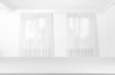 Image of Empty white table against windows with curtains in room