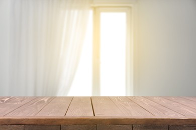 Image of Empty wooden table against window with curtain in room