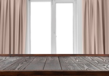Image of Empty wooden table against window with curtains in room
