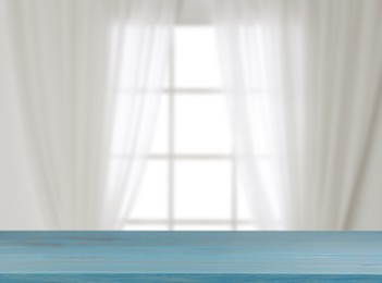 Image of Empty wooden table against window with curtains in room