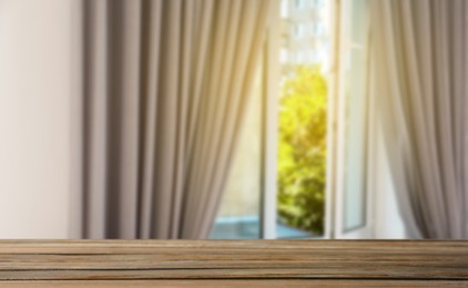 Image of Empty wooden table against window with curtains in room