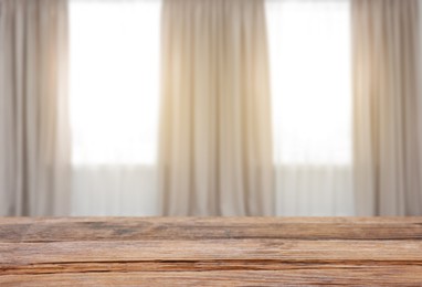 Image of Empty wooden table against windows with curtains in room