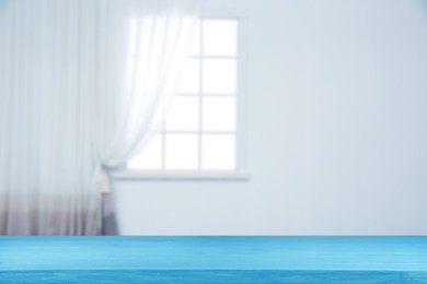 Image of Empty wooden table against window with curtain in room