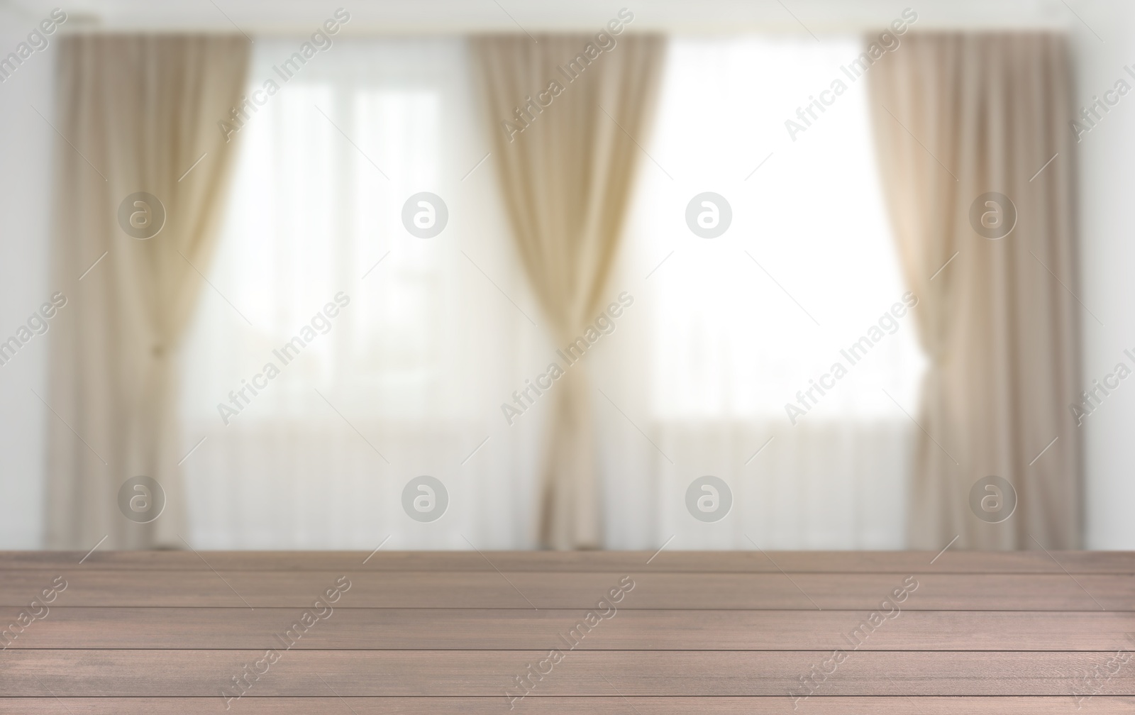 Empty wooden table against windows with curtains in room Image of Empty wooden table against windows with curtains in room