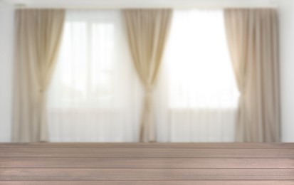 Image of Empty wooden table against windows with curtains in room