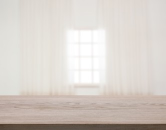 Image of Empty wooden table against window with curtains in room