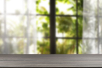 Image of Empty wooden table against window with curtains in room