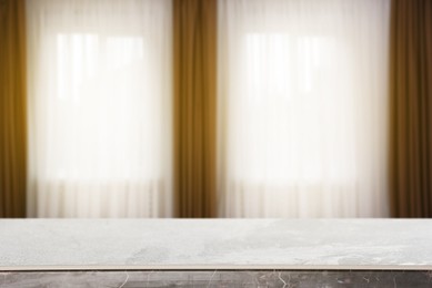 Image of Empty stone table against windows with curtains in room