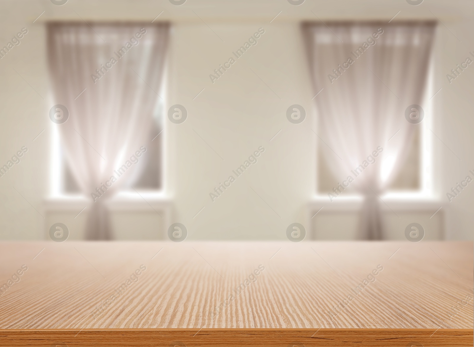 Empty wooden table against windows with curtains in room Image of Empty wooden table against windows with curtains in room