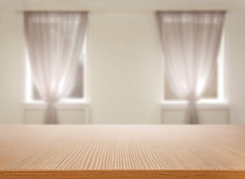 Image of Empty wooden table against windows with curtains in room
