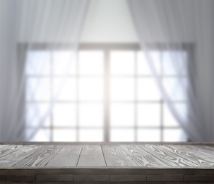 Image of Empty wooden table against window with curtains in room