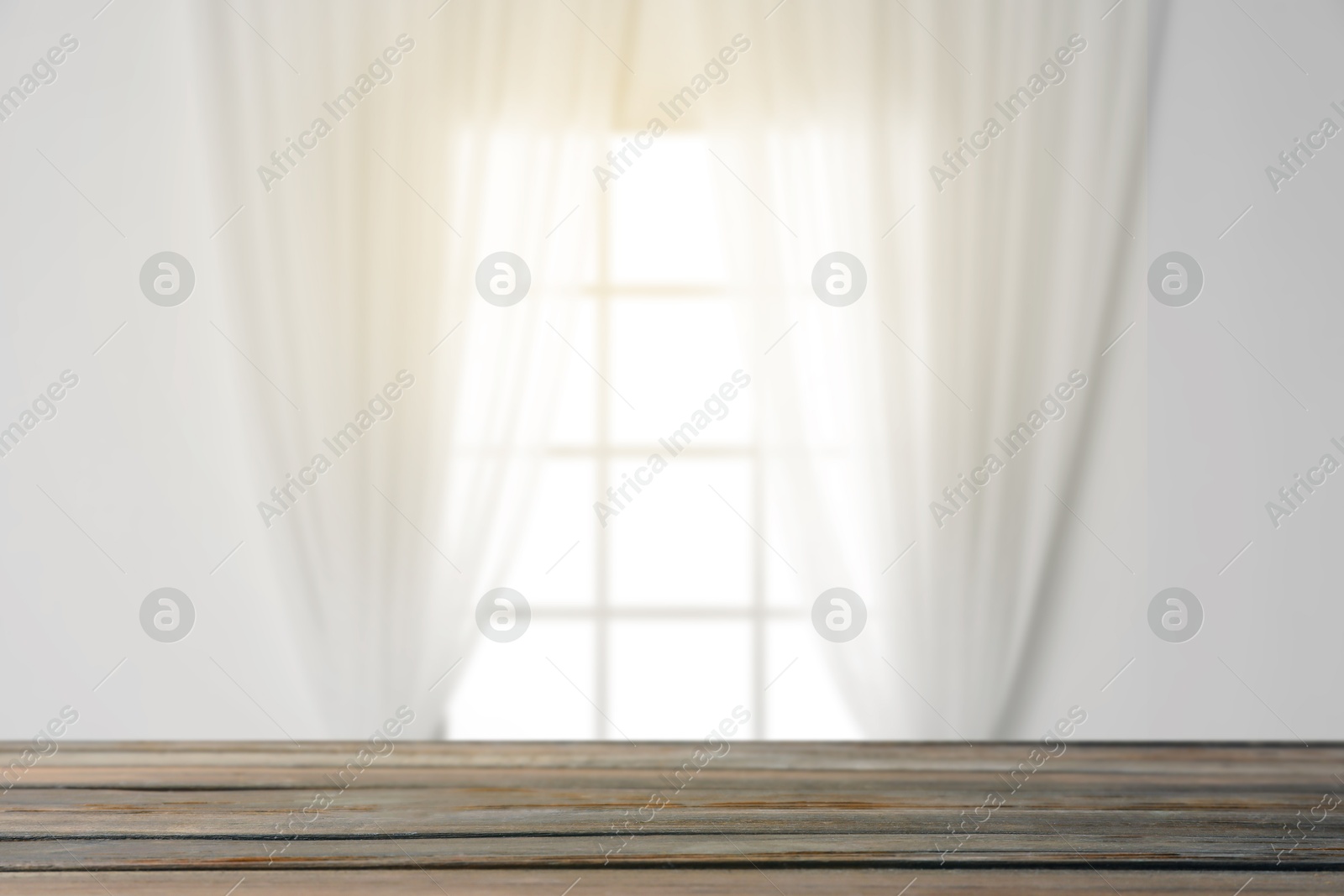 Image of Empty wooden table against window with curtains in room