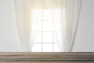 Image of Empty wooden table against window with curtains in room