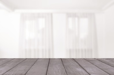 Image of Empty wooden table against windows with curtains in room