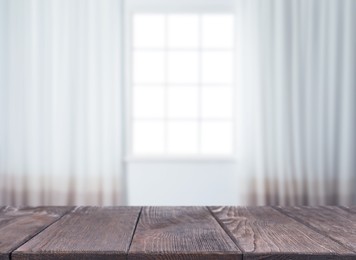 Image of Empty wooden table against window with curtains in room