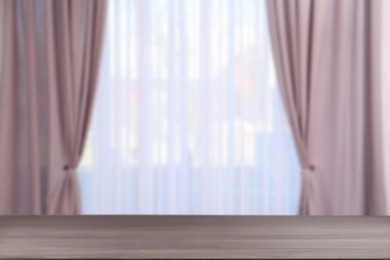 Image of Empty wooden table against window with curtains in room