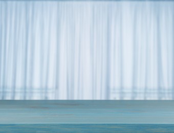 Image of Empty wooden table against window with curtains in room