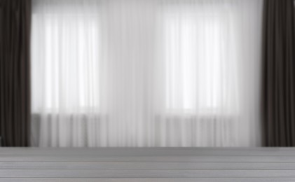 Image of Empty wooden table against window with curtains in room