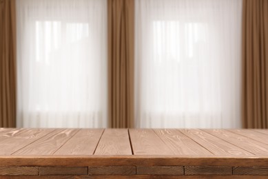 Image of Empty wooden table against windows with curtains in room