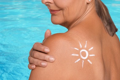 Image of Woman with sun protection product on her shoulder by outdoor swimming pool, closeup