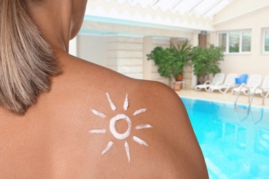 Image of Woman with sun protection product on her shoulder by swimming pool, closeup