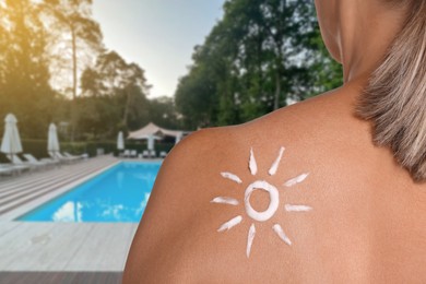 Image of Woman with sun protection product on her shoulder by outdoor swimming pool, closeup