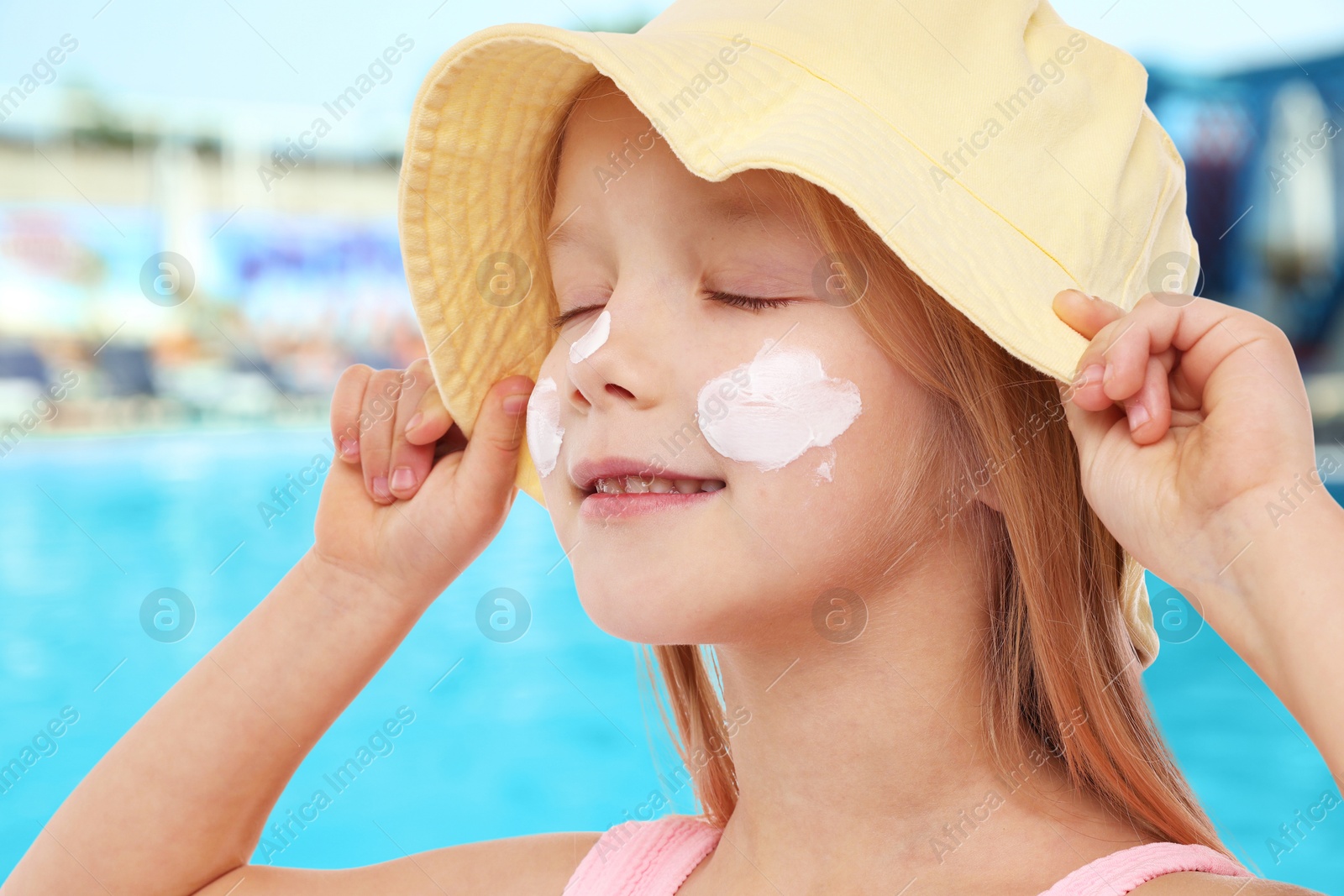 Cute little girl with sun protection product on her cheek by outdoor swimming pool Image of Cute little girl with sun protection product on her cheek by outdoor swimming pool