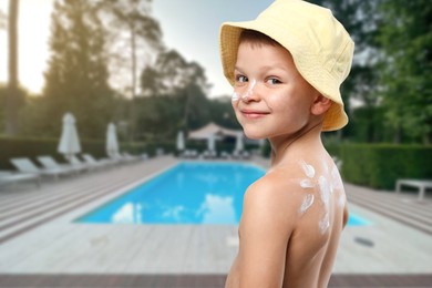 Image of Little boy with sun protection product on his skin by outdoor swimming pool