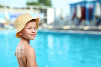 Image of Little boy with sun protection product on his skin by outdoor swimming pool